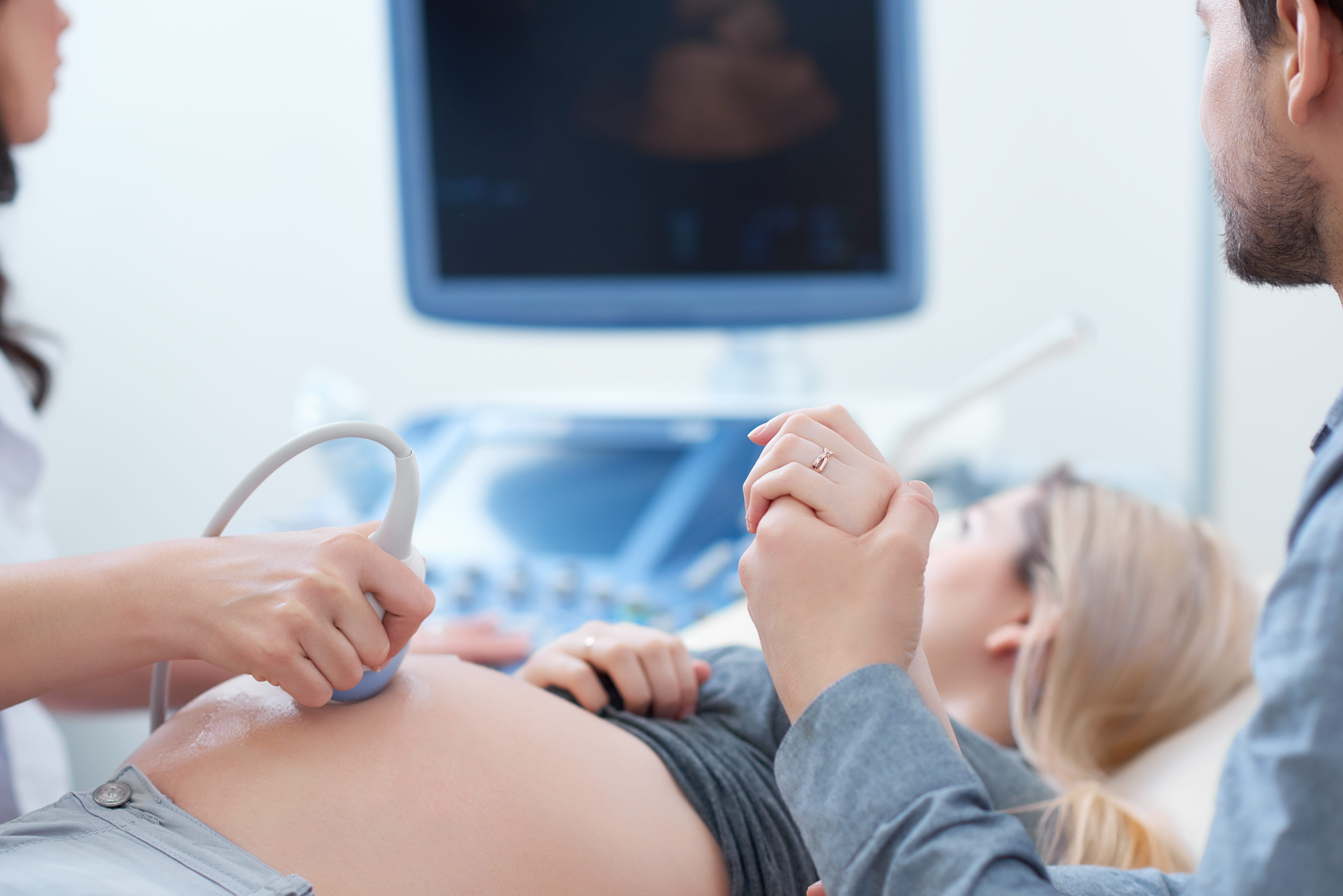 Husband holding hand his wife during ultrasound diagnostic. pregnant woman getting ultrasound